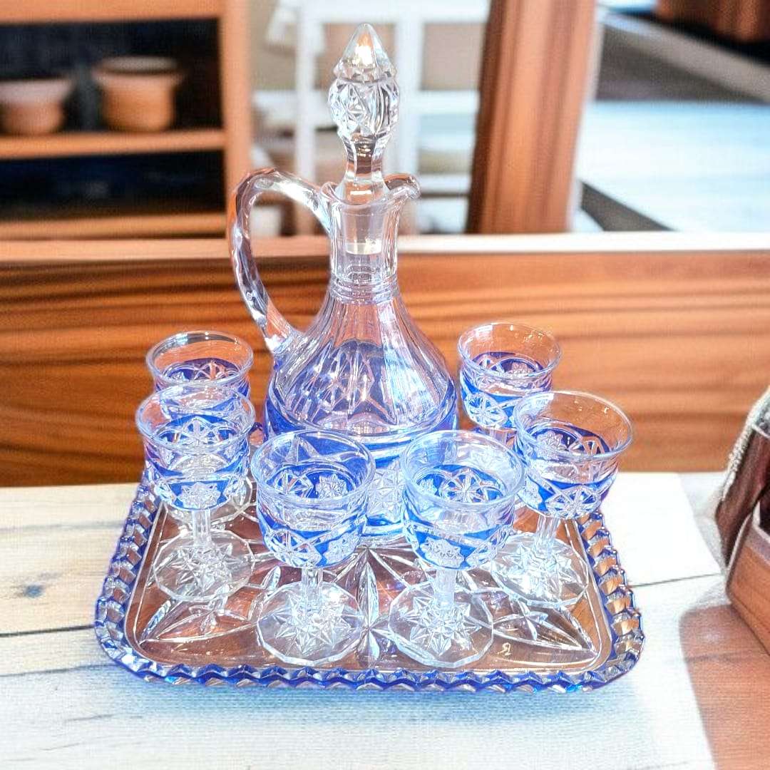 Juego de licorera con copas de cristal azul tallado sobre bandeja decorativa, ideal para decoración elegante en el hogar o jardín.