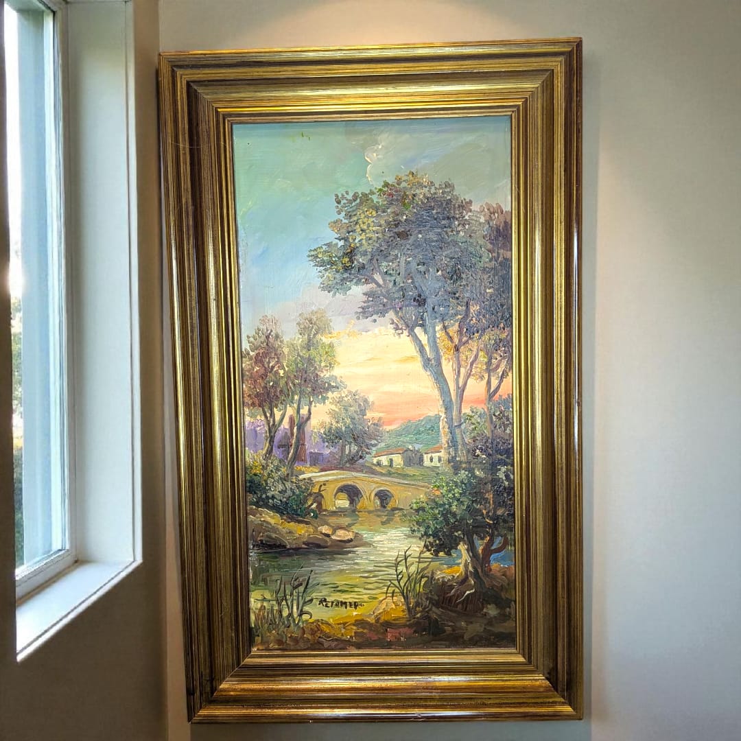 Cuadro de Retamero al óleo, paisaje con puente y río, original enmarcado en dorado, colgado en pared de pasillo interior iluminado.