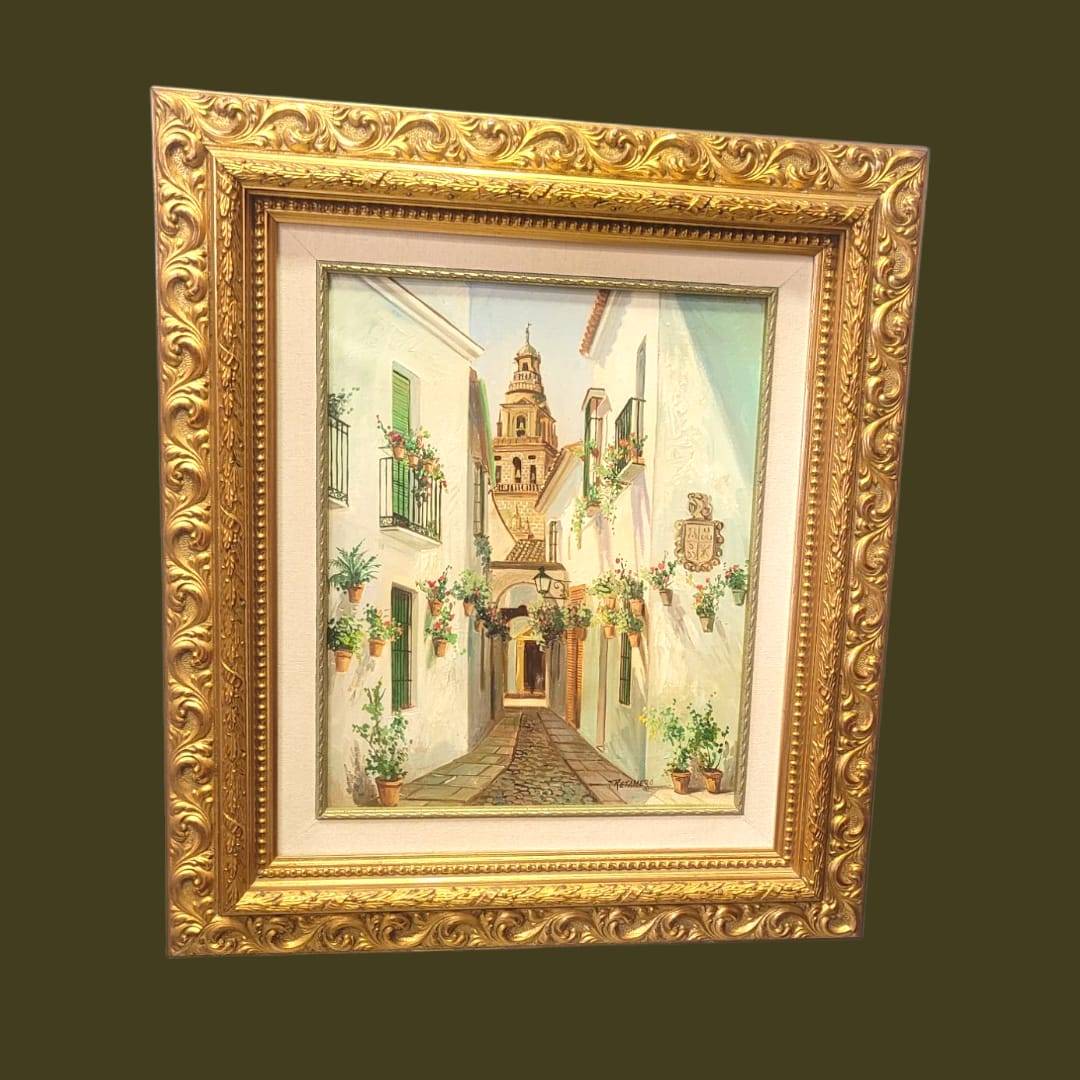 Cuadro al óleo Retamero – Calle típica andaluza con flores y torre al fondo, enmarcado en marco dorado tallado, ideal para decoración de hogar.