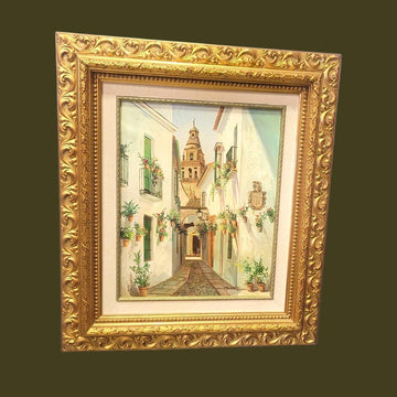 Cuadro al óleo Retamero – Calle típica andaluza con flores y torre al fondo, enmarcado en marco dorado tallado, ideal para decoración de hogar.