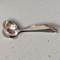 Cucharón de metal plateado antiguo con diseño curvo, ideal para una mesa clásica. Utensilio elegante para servir sopas en decoración vintage.