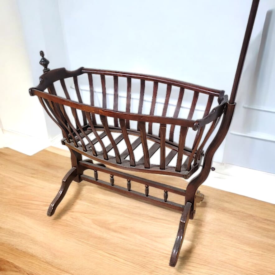 Cuna mecedora estilo Art Nouveau de Viena, fabricada entre 1890 y 1920, con detalles florales y líneas curvas en madera oscura.