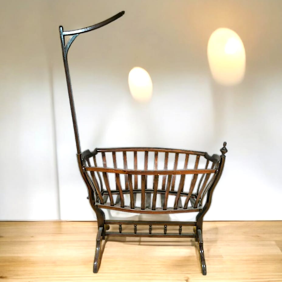 Cuna mecedora estilo Art Nouveau de Viena, fabricada entre 1890 y 1920, con detalles florales y líneas curvas en madera oscura.