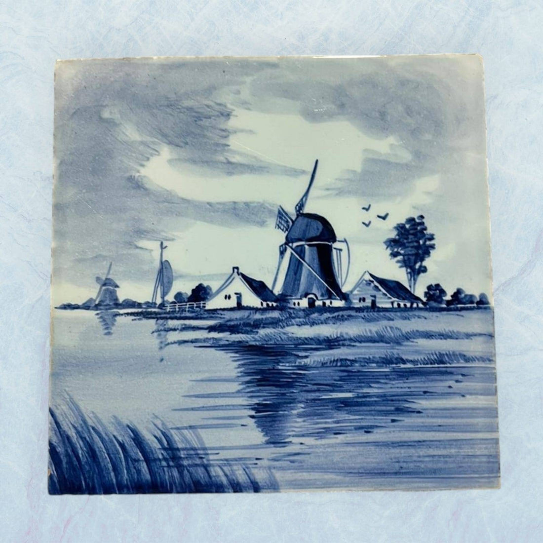Azulejo holandés pintado a mano estilo Delft Blue con molino de viento y casas rurales. Decoración cerámica tradicional para pared.