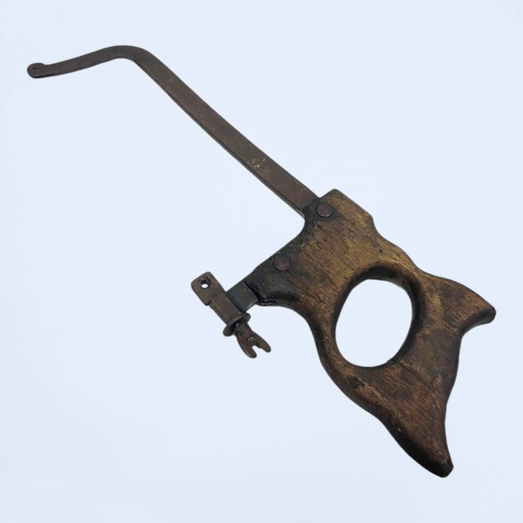 Antigua sierra sin hoja con mango de madera desgastado, ideal para restauración y decoración vintage en talleres o espacios rústicos.