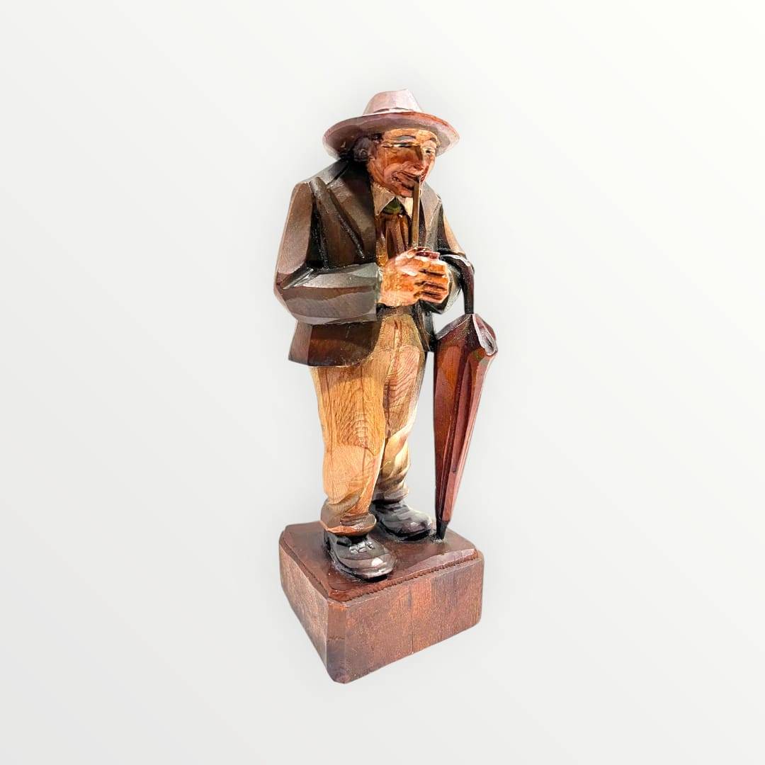 Figura de hombre mayor en madera con sombrero y paraguas, estilo rústico europeo. Pieza decorativa artesanal para espacios clásicos.