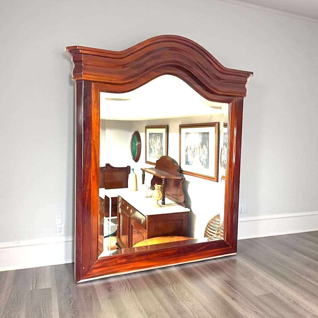 Espejo de caoba con cristal biselado clásico antiguo, marco robusto con copete curvo, ideal para decoración elegante en salones o recibidores.