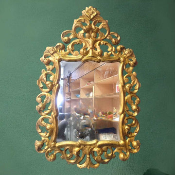 Espejo cornucopia ornamental dorado con marco tallado en estilo barroco, ideal para una decoración elegante en interiores clásicos.