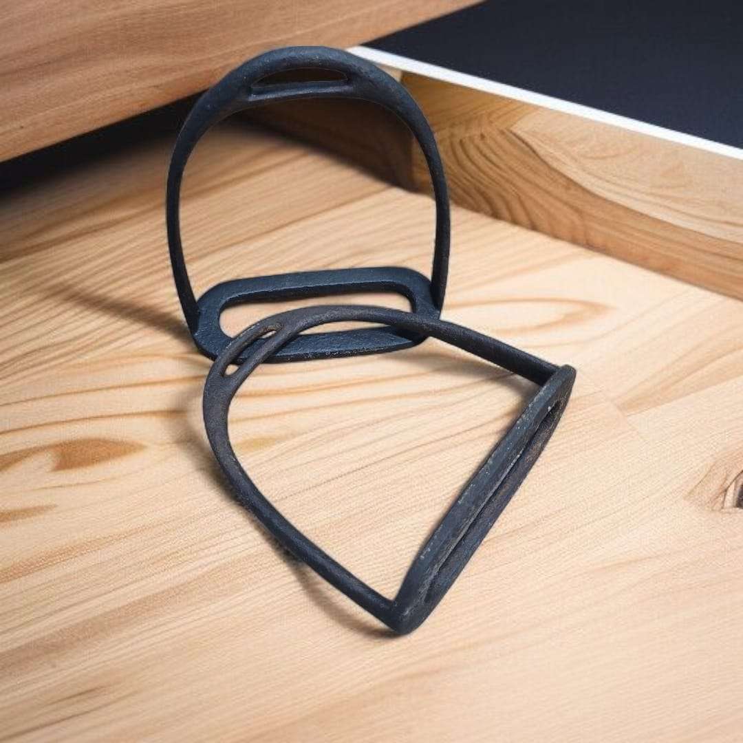 Pareja de estribos antiguos sobre madera clara, mostrando su curvatura superior.