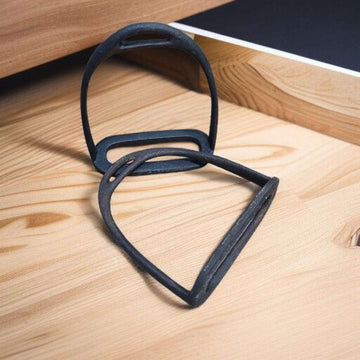 Pareja de estribos antiguos sobre madera clara, mostrando su curvatura superior.