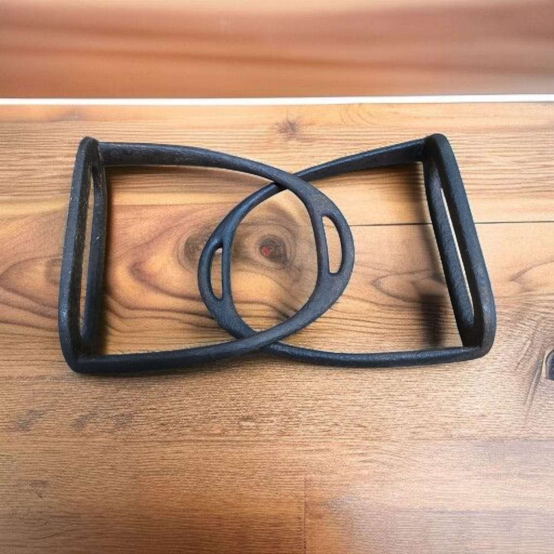 Pareja de estribos antiguos sobre madera clara, mostrando su curvatura superior.