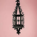 Vista frontal del farol de forja colgante antiguo con fondo rosa