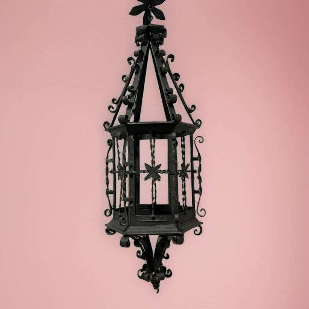 Vista frontal del farol de forja colgante antiguo con fondo rosa