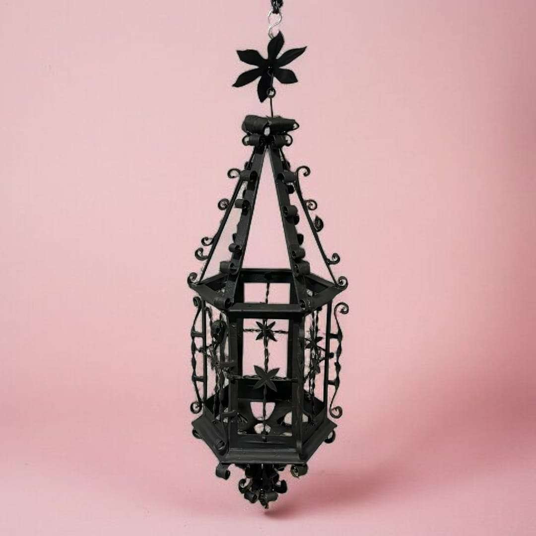 Vista frontal del farol de forja colgante antiguo con fondo rosa