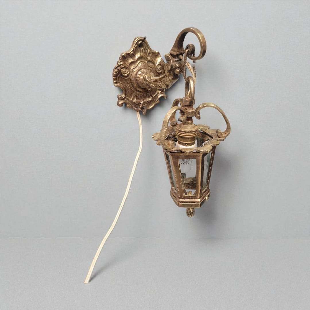 Vista superior del farolillo de bronce antiguo montado en pared, con soporte ornamentado y cableado expuesto para decoración clásica.