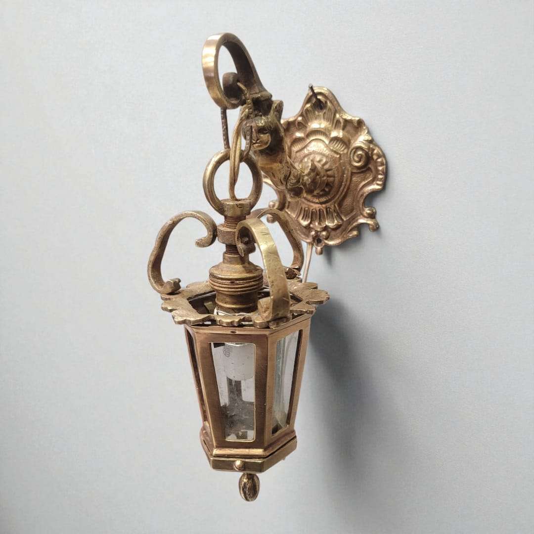 Farolillo de bronce antiguo para pared decorativa funcional con vidrio transparente y detalles curvos, ideal para ambientes elegantes.