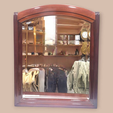 Espejo de caoba con cristal biselado y marco arqueado, ideal para decoración clásica en interiores elegantes. Calidad artesanal en cada detalle.