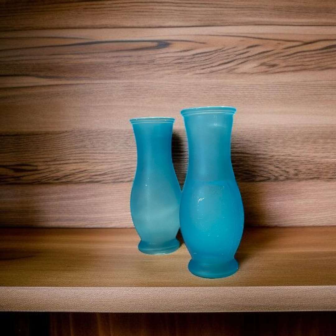 Floreros de cristal celeste en mesa de madera, decoración elegante.