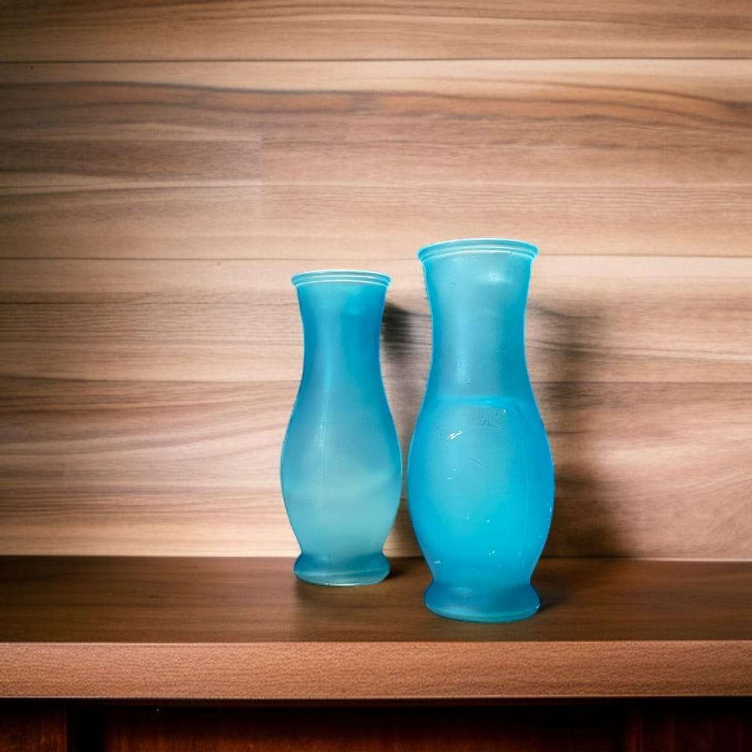 Floreros de cristal celeste en mesa de madera, decoración elegante.