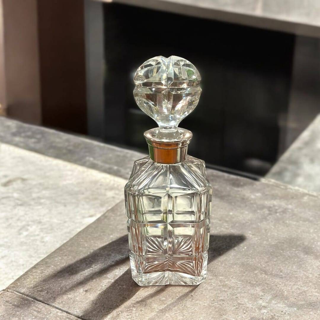 Licorera de cristal tallado con cuello de metal plateado única, diseño geométrico elegante ideal para decoración de interiores sofisticados.