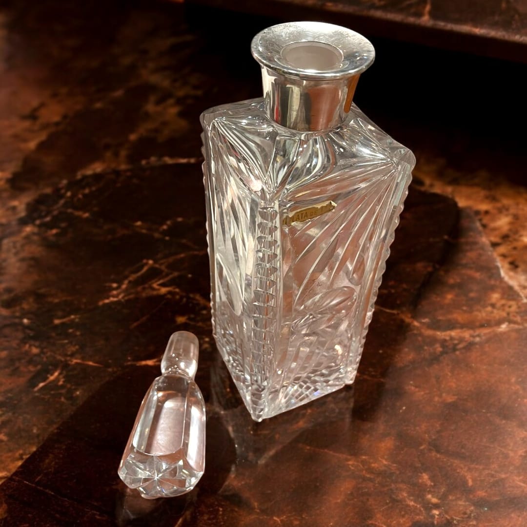 Licorera de cristal tallado con cuello de metal plateado única, diseño geométrico elegante ideal para decoración de interiores sofisticados.