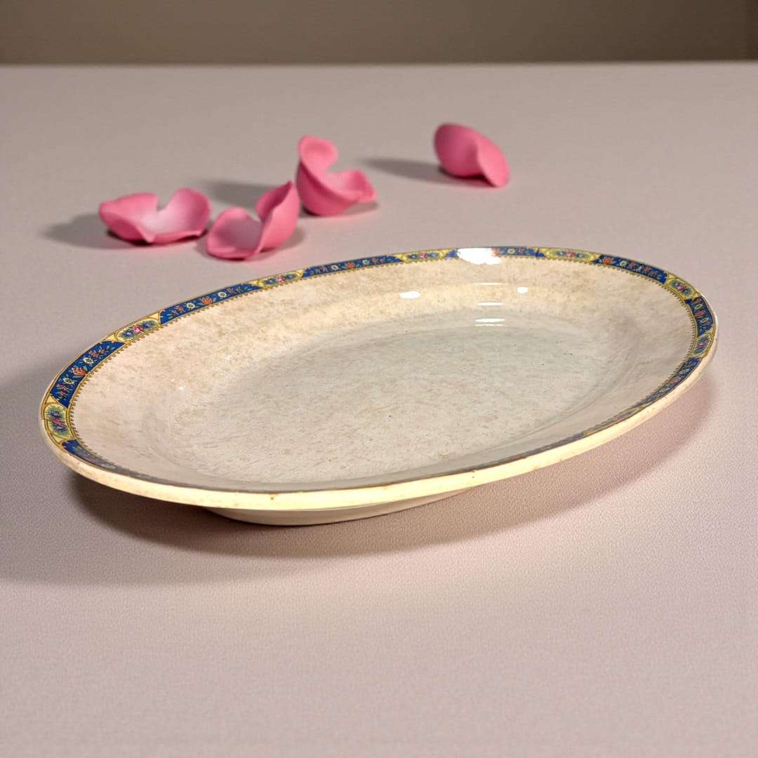 Fuente de loza Pickman colocada sobre mesa rústica en exterior.