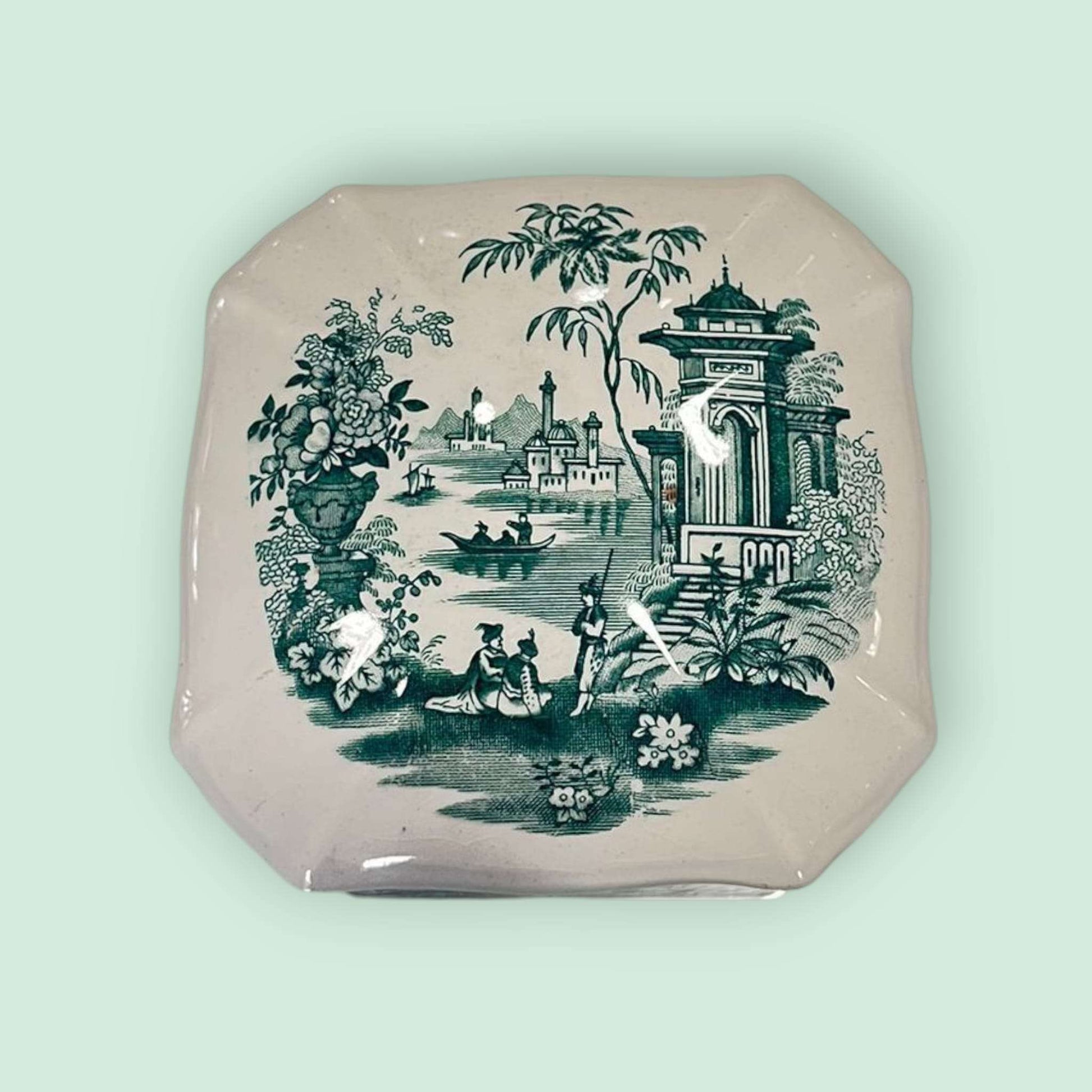 “Detalle superior de la tapa de la galletera de loza con escena decorada.”