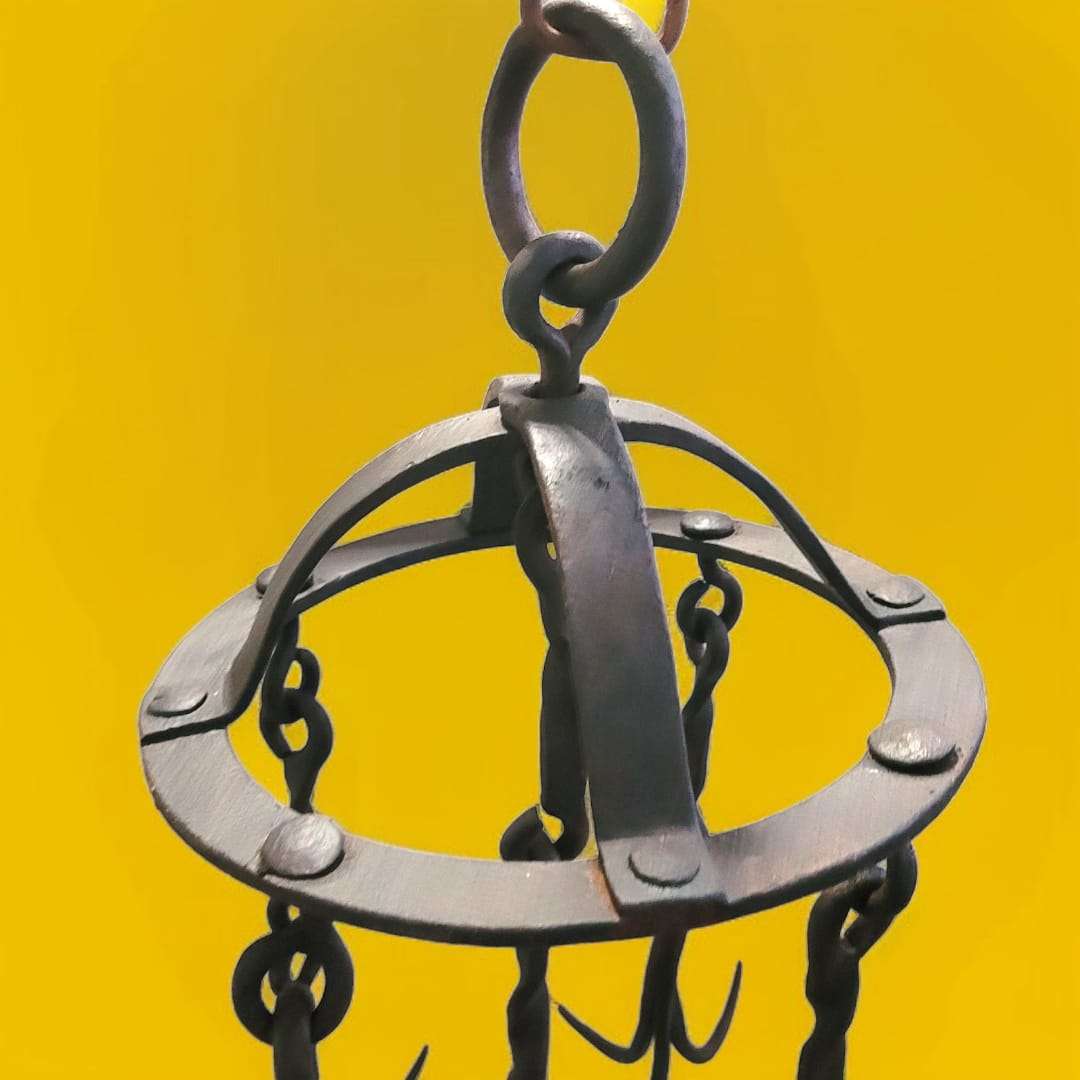 Gancho de pozo de hierro forjado visto desde arriba, con anillas entrelazadas.