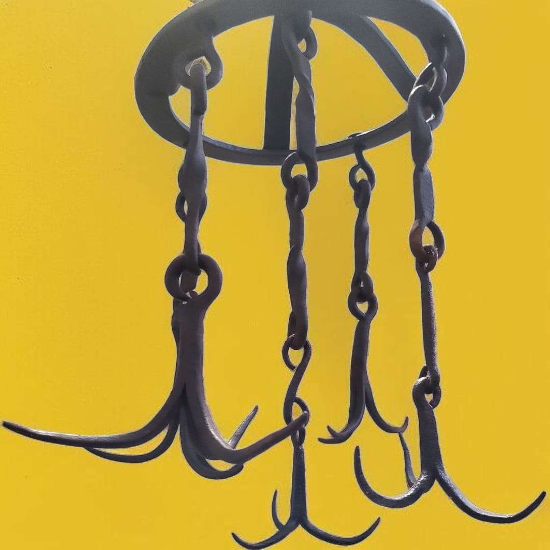 Detalle de los ganchos curvados colgando, con torsiones artesanales en las cadenas.