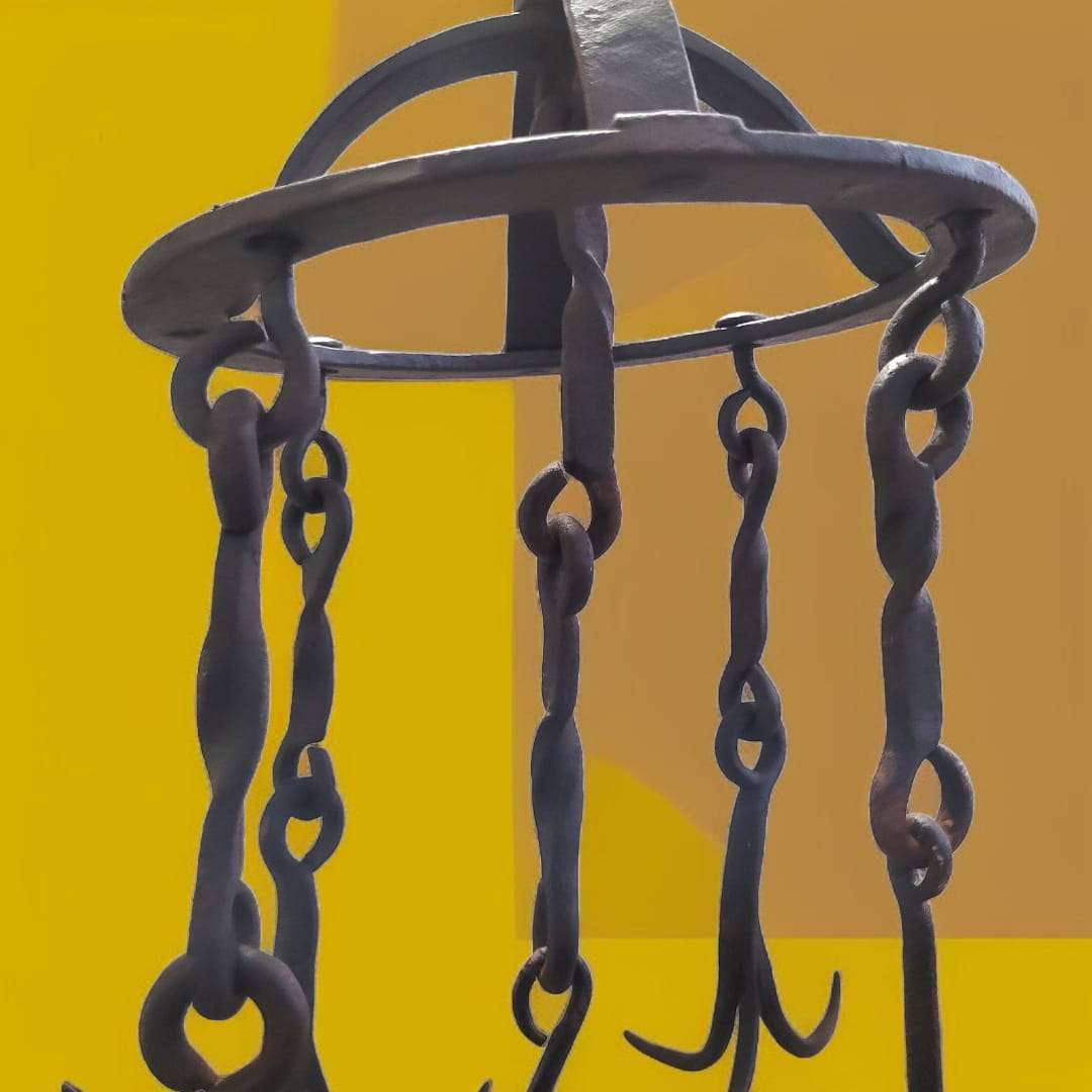 Gancho de pozo antiguo en hierro con cinco cadenas torsionadas y ganchos curvos.

