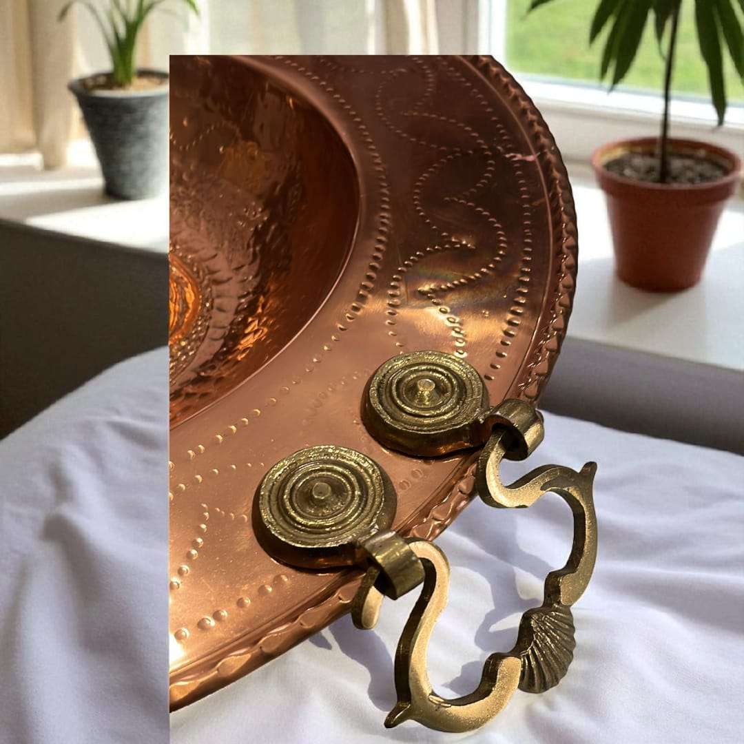 Brasero de cobre artesanal con relieve griego y asas laterales.