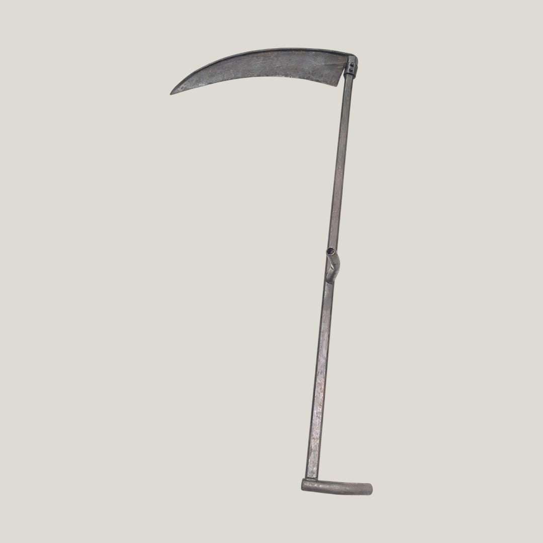 Vista completa de guadaña antigua decorativa de hierro forjado tradicional, con diseño auténtico de herramienta agrícola clásica.