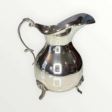Jarra de metal plateado con diseño clásico y patas ornamentadas, ideal para decoración elegante en el hogar. Elegancia clásica y diseño intemporal.