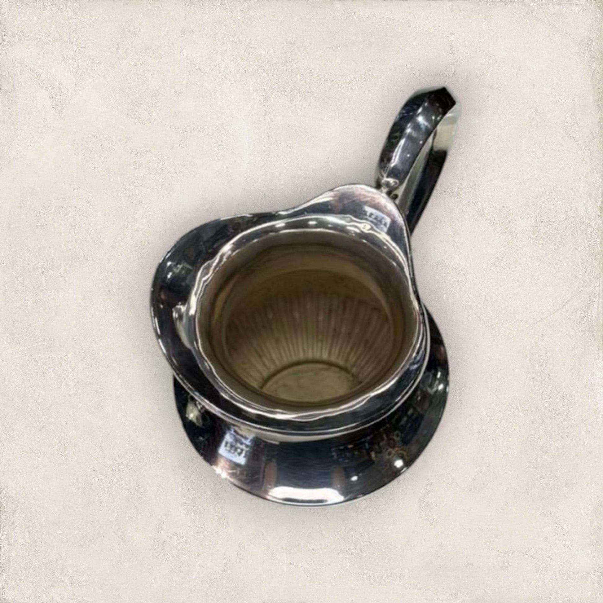 Vista superior de jarra de metal plateado mostrando interior amplio y detalles clásicos, perfecta para uso decorativo o funcional.