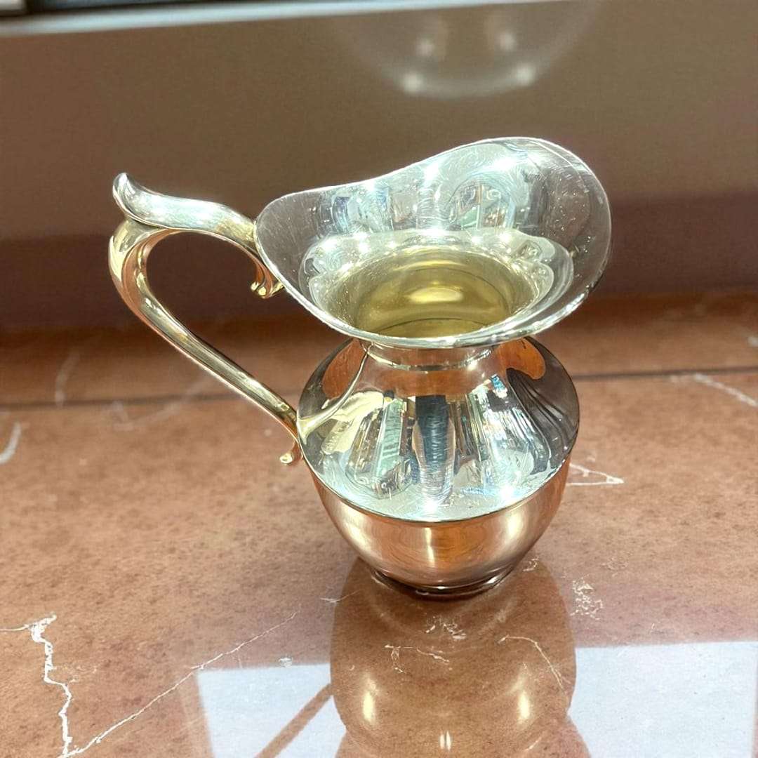 Jarra de metal plateado con acabado pulido reflejando la luz.