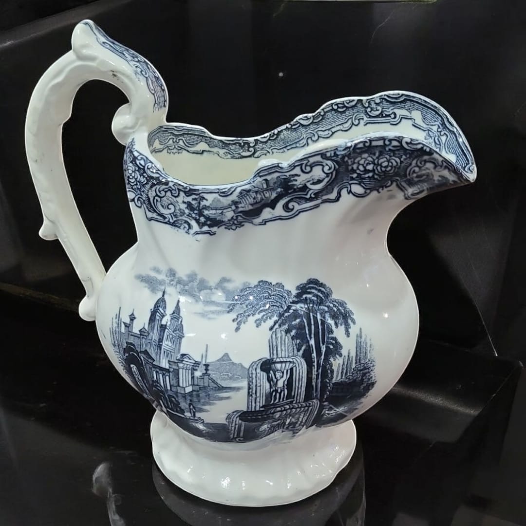 Jarra de Pickman con diseño vintage en cerámica blanca y azul, decorada con escenas clásicas. Pieza exclusiva para decoración y colección.