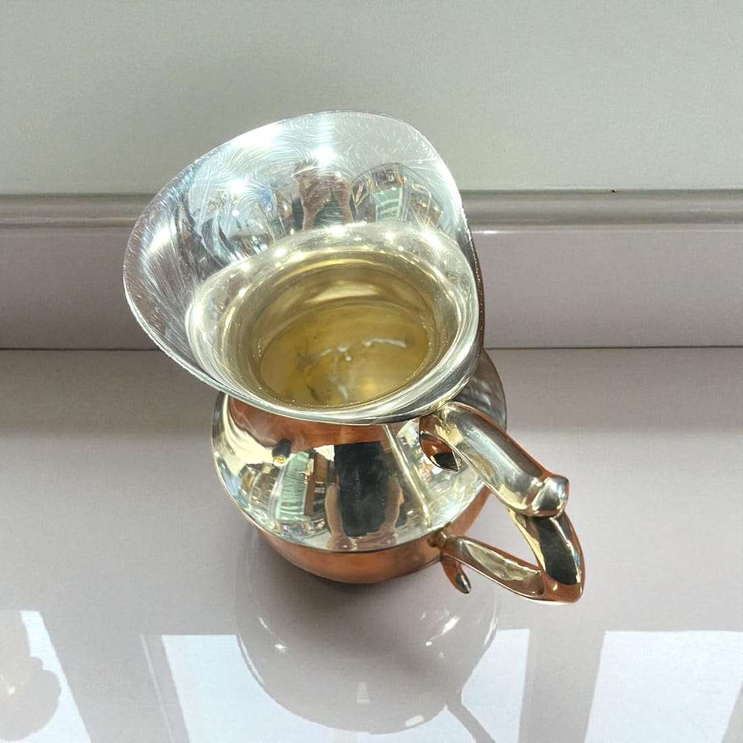 Detalle de la boquilla ancha de la jarra de metal plateado.