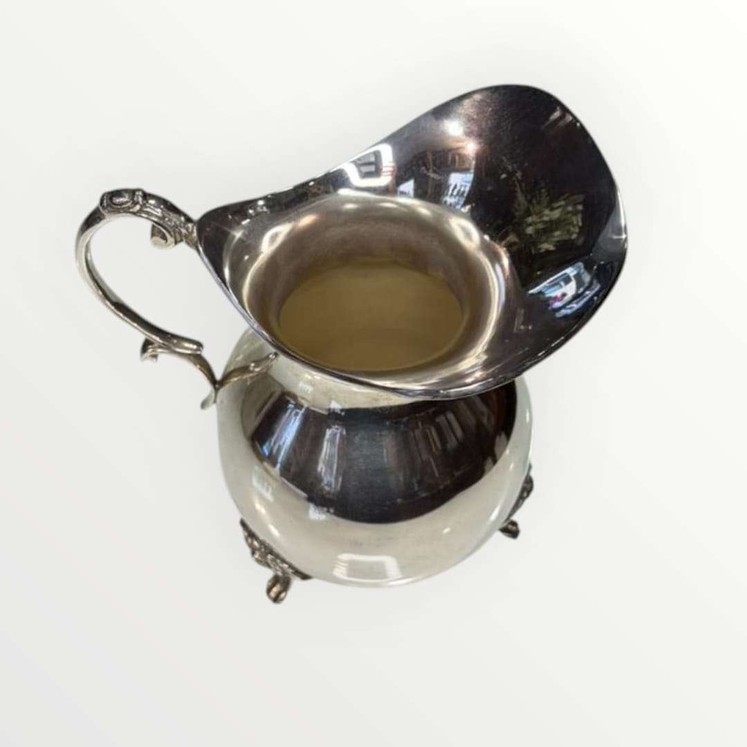 Jarra de metal plateado con diseño clásico y acabado brillante, ideal para decoración elegante en el hogar. Pieza única de estilo intemporal.