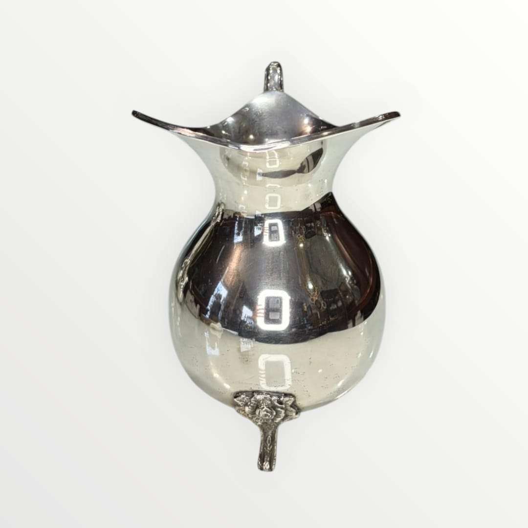 Jarra de metal plateado con diseño intemporal y acabado brillante, ideal para decoración elegante en interiores clásicos.