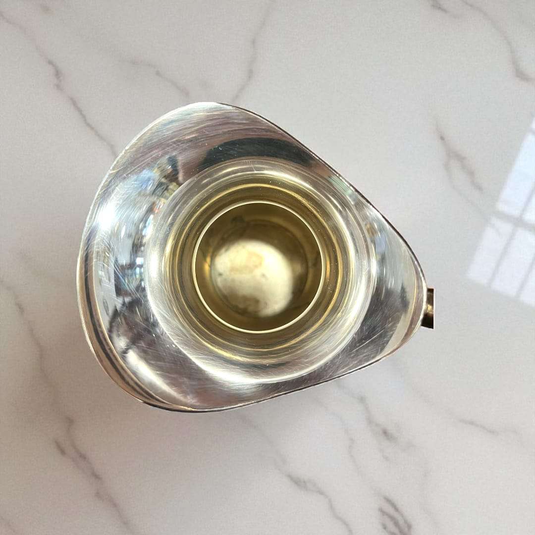 Jarra de metal plateado con diseño clásico y cuerpo abombado.