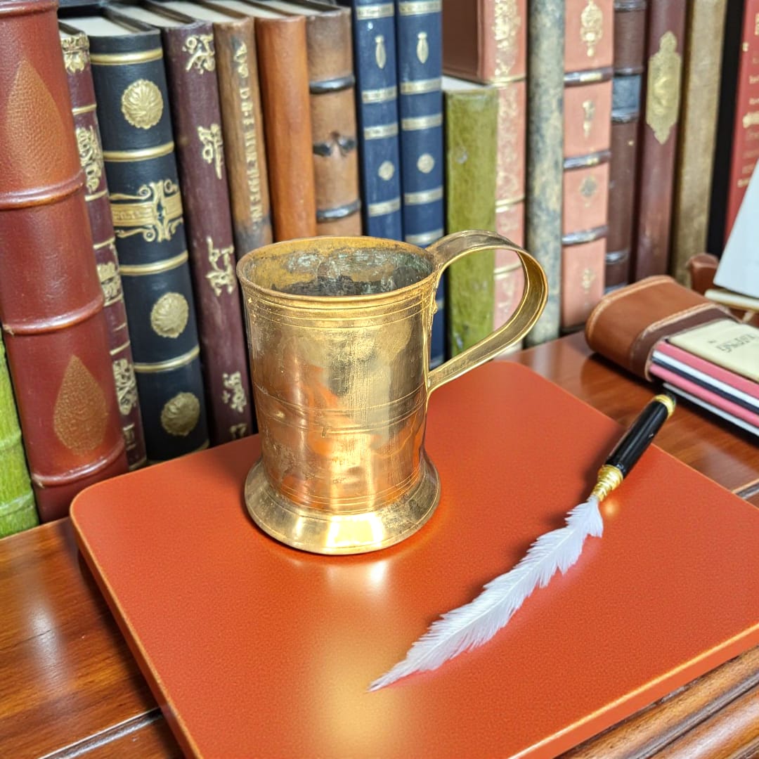 Jarra de Cerveza Alemana en metal vintage coleccionista sobre escritorio con libros antiguos. Decoración ideal para amantes de la cervecería clásica.