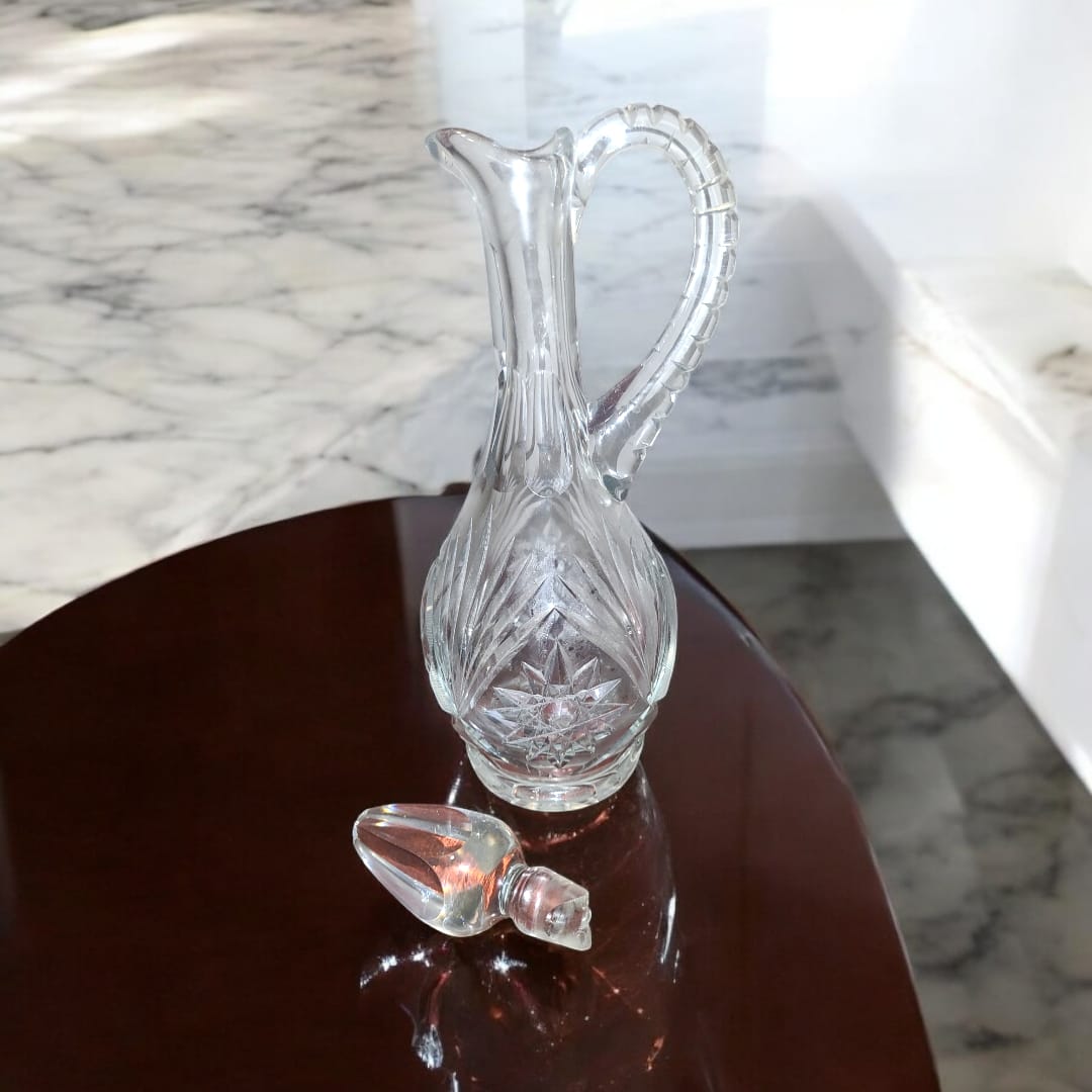 Jarra licorera de cristal tallada con diseño elegante y tapa en forma de gota, ideal para decoración o servir licores.