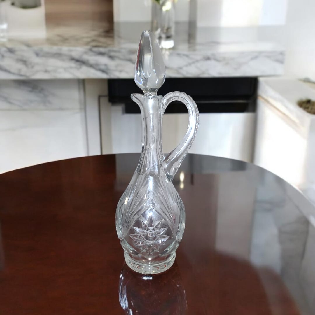 Jarra licorera de cristal tallada con asa elegante y tapa en forma de gota, perfecta para servir licores en reuniones.