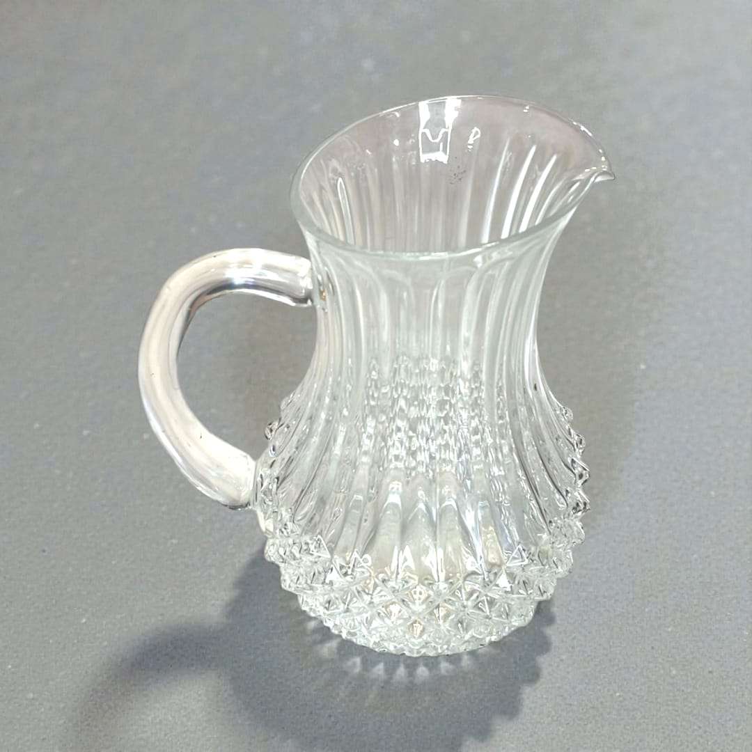 Jarra de cristal tallado elegante y funcional con asa integrada y pico vertedor. Ideal para decoración de interiores en estilo clásico.