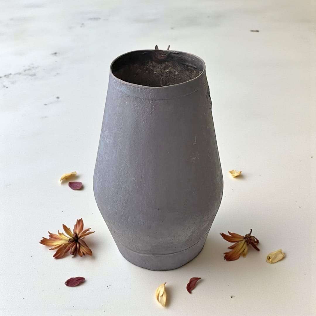 Jarra de trasiego antigua en metal con forma cónica, pieza vinícola única ideal para decoración rústica en hogar o jardín.