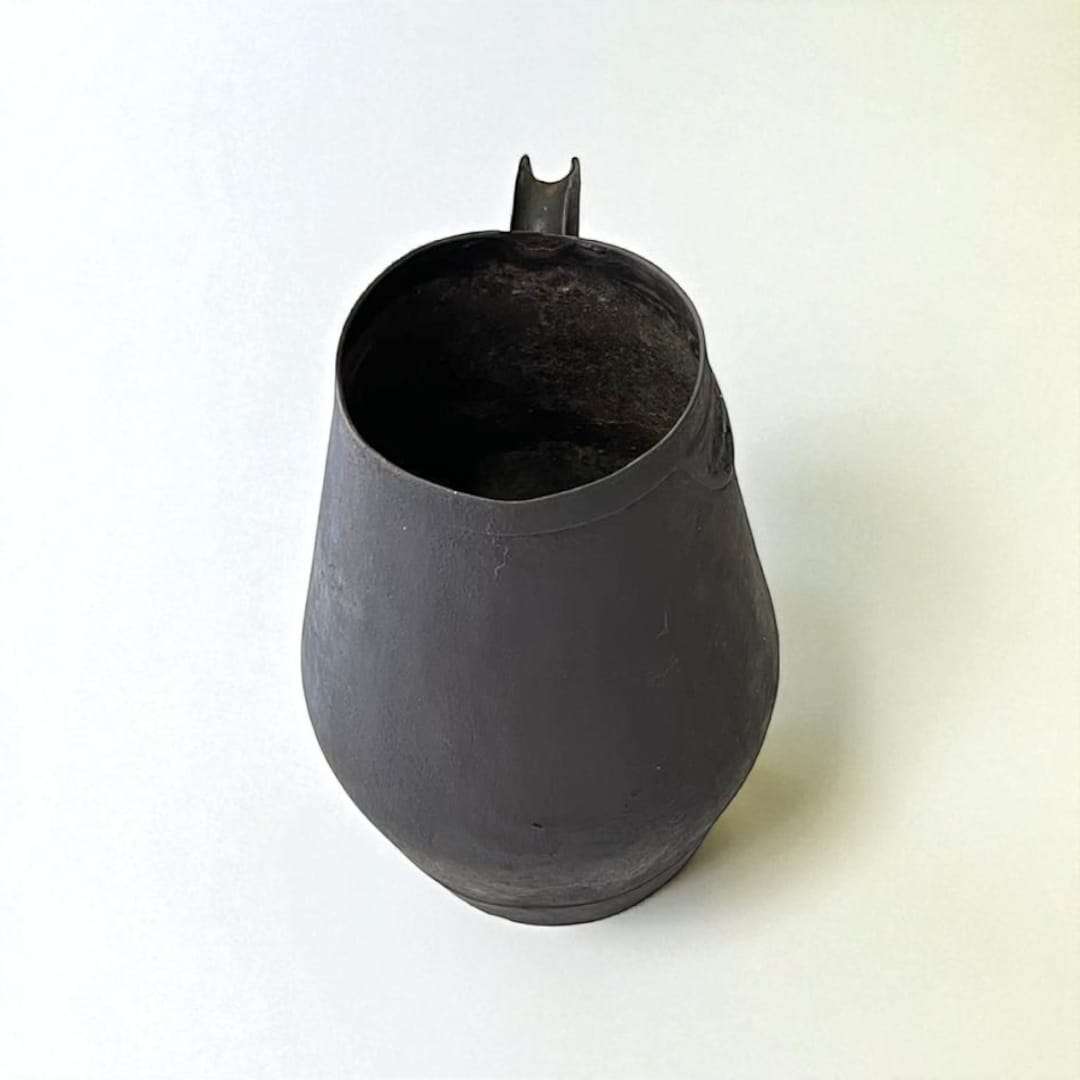 Jarra de trasiego antigua en metal con acabado envejecido, ideal como decoración vinícola rústica para el hogar o jardín.