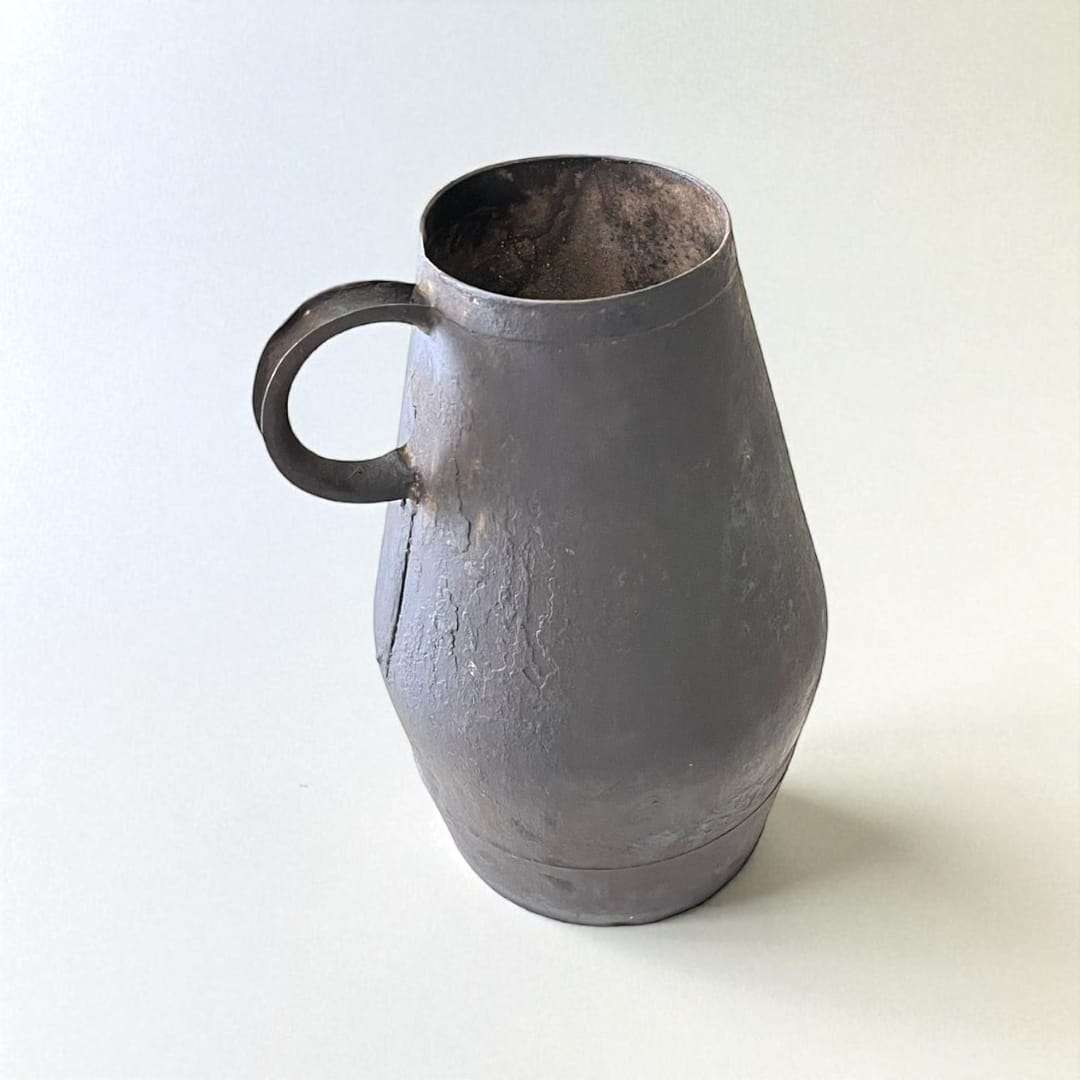 Jarra de trasiego antigua en metal con acabado envejecido, ideal como decoración vinícola rústica para el hogar o jardín.