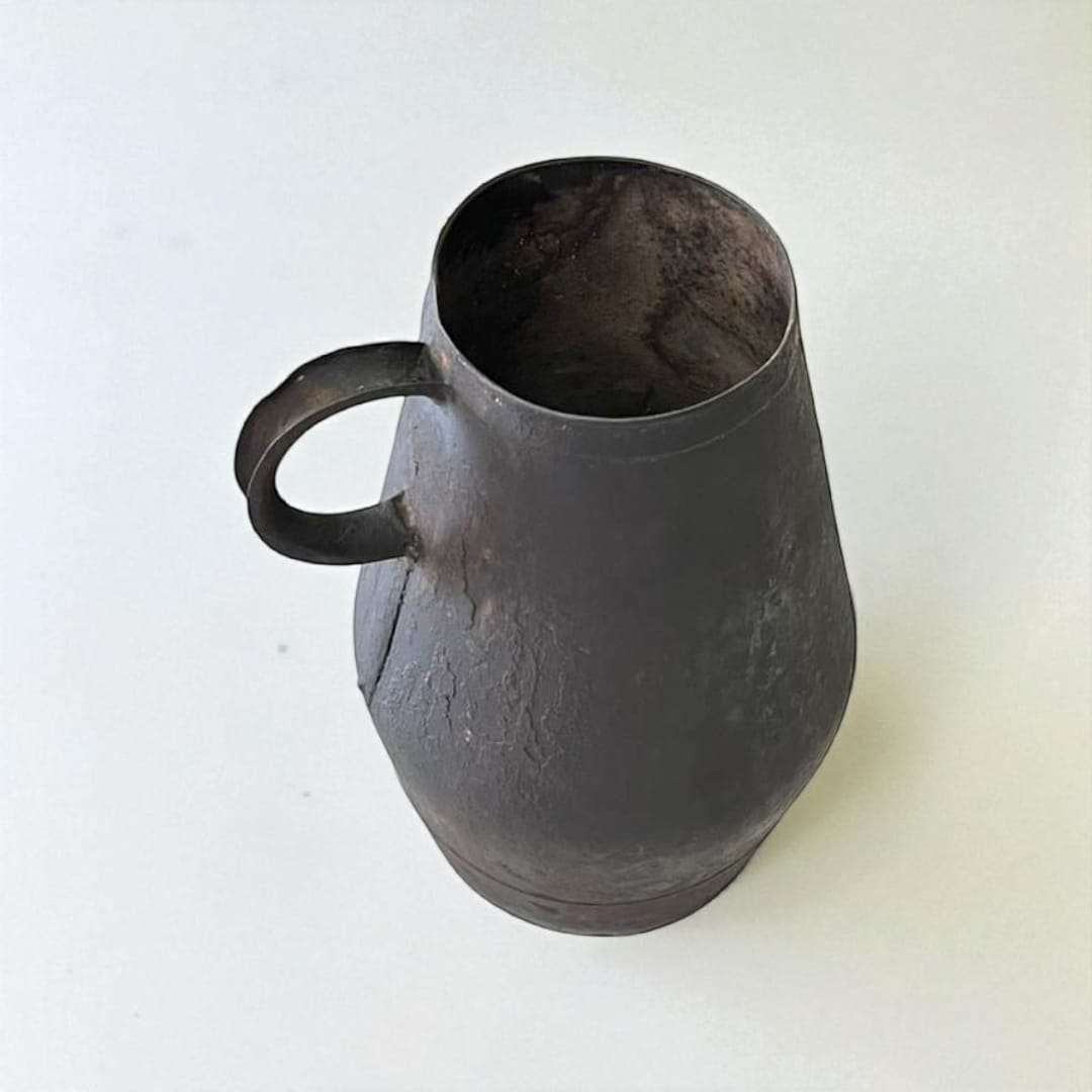 Jarra de trasiego antigua en metal con acabado envejecido, ideal como decoración vinícola rústica para el hogar o jardín.