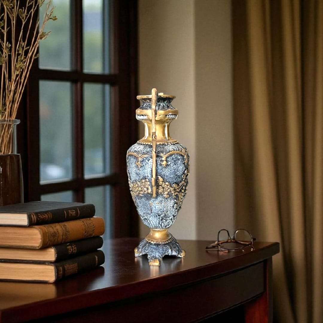 Jarrón de bronce con asas ornamentales y base decorada en relieve.