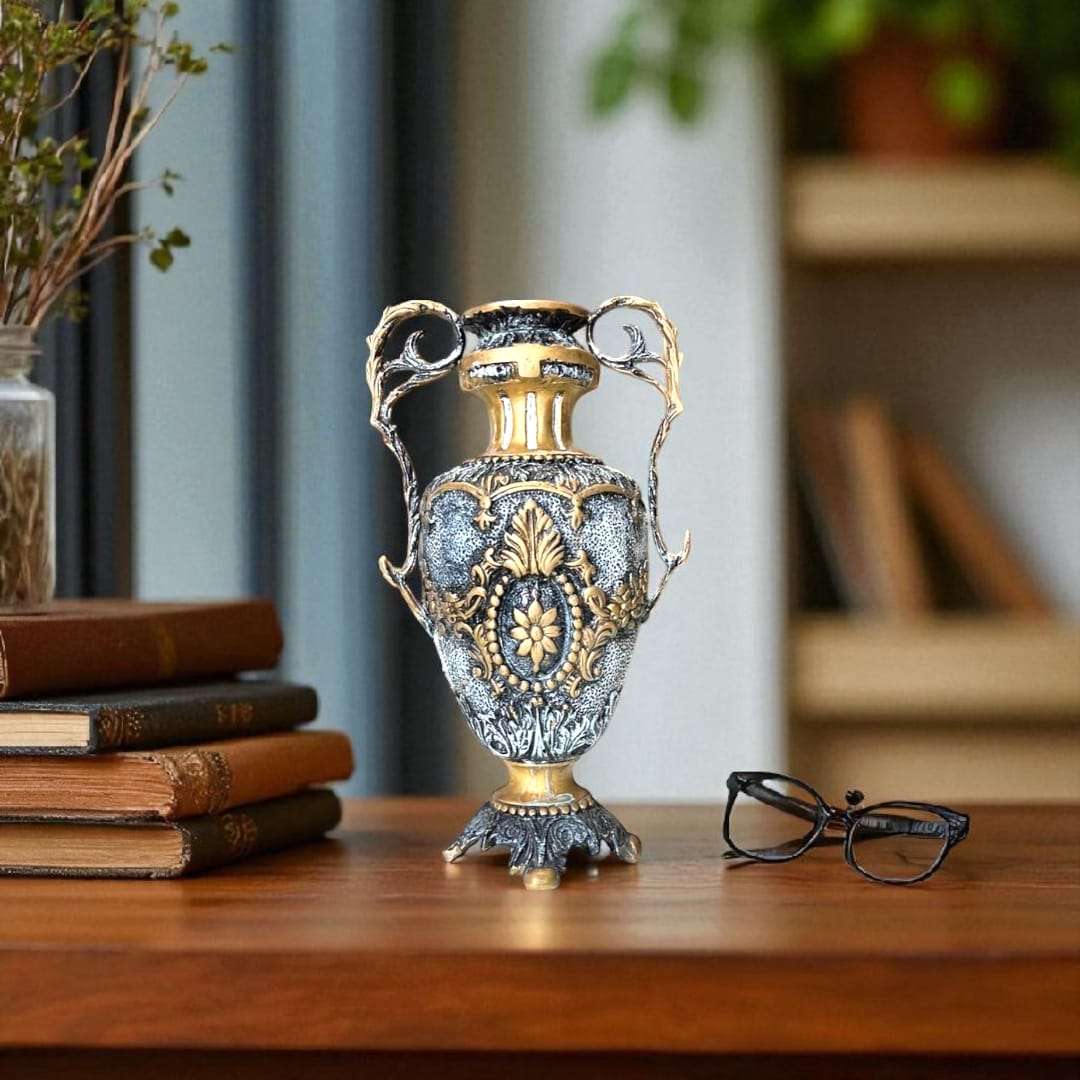 Jarrón de bronce con relieves dorados en mesa de madera, detalle clásico.